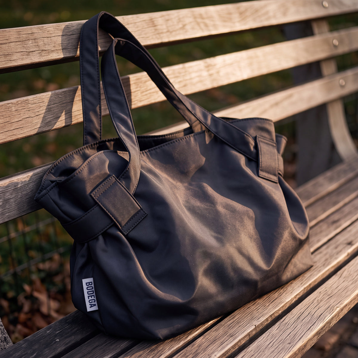 Bodega Bag in Bodega Black as a tote on a wooden park bench