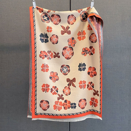 Soft tassel winter shawl wrap in orange hanging flat showing the flower and clover print
